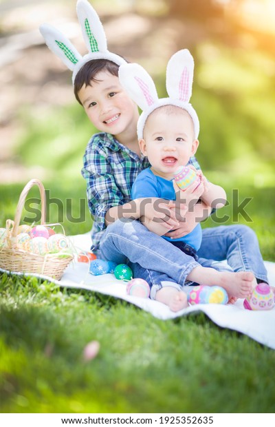 Mixed Race Chinese and Caucasian Boys Outside in\
Park Playing with Easter\
Eggs.