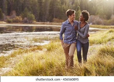 Mixed race couple embracing, walking near a rural lake - Powered by Shutterstock