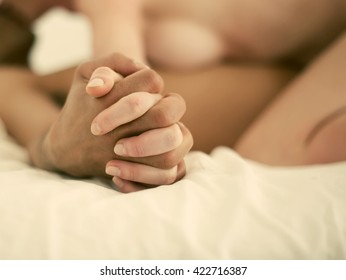 Mixed race couple making love in bed - focus on hand