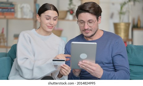 Mixed Race Couple Making Successful Online Shopping On Tablet At Home