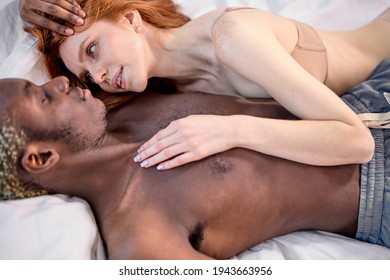 Mixed Race Couple Redhead Woman With Black Boyfriend Lying On Bed Close To Each Other On Bed At Home