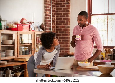 Mixed Race Couple Using Laptop Computer In Kitchen