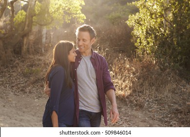 Mixed race couple walking in park embracing, waist up - Powered by Shutterstock