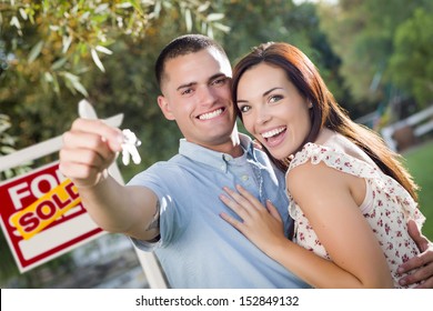 Mixed Race Excited Military Couple With New House Keys And Sold Real Estate Sign Outside.