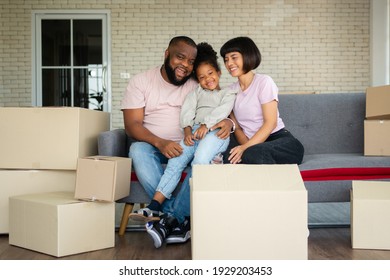 Mixed Race Families Are Sitting On The Sofa For Rest After Moving To A New House On The First Day After Buying Real Estate.  Concept Of Starting A New Life For A New Family.