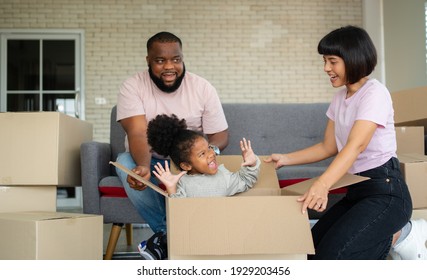 Mixed Race Families Are Sitting On The Sofa For Rest After Moving To A New House On The First Day After Buying Real Estate.  Concept Of Starting A New Life For A New Family.