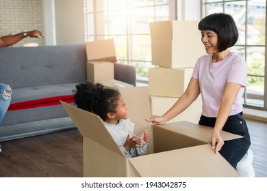 Mixed Race Families Are Sitting On The Sofa For Rest After Moving To A New House On The First Day After Buying Real Estate.  Concept Of Starting A New Life For A New Family.