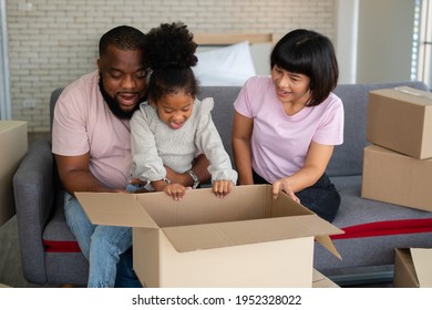 Mixed Race Families Are Sitting On The Sofa And Surprised After Open The Gift Box From A Neighbor On The First Day After Moving House.  Concept Of Starting A New Life For A New Family.