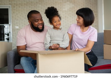 Mixed Race Families Are Sitting On The Sofa For Rest After Moving To A New House On The First Day After Buying Real Estate.  Concept Of Starting A New Life For A New Family.