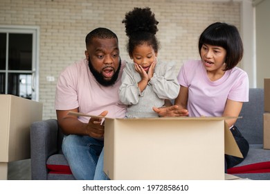 Mixed Race Families Are Sitting On The Sofa And Surprised After Open The Gift Box From A Neighbor On The First Day After Moving House.  Concept Of Starting A New Life For A New Family.