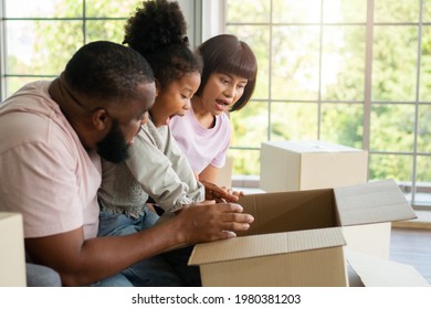 Mixed Race Families Are Sitting On The Sofa And Surprised After Open The Gift Box From A Neighbor On The First Day After Moving House.  Concept Of Starting A New Life For A New Family.