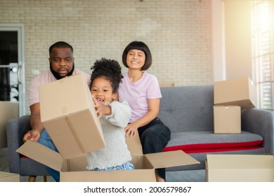 Mixed Race Families Are Sitting On The Sofa For Rest After Moving To A New House On The First Day After Buying Real Estate.  Concept Of Starting A New Life For A New Family.