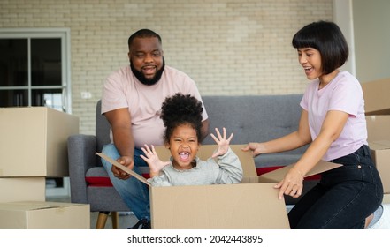 Mixed Race Families Are Sitting On The Sofa For Rest After Moving To A New House On The First Day After Buying Real Estate.  Concept Of Starting A New Life For A New Family.