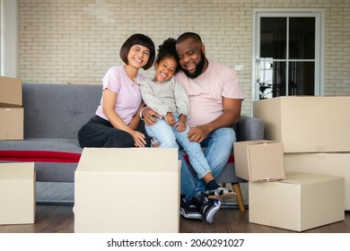 Mixed Race Families Are Sitting On The Sofa For Rest After Moving To A New House On The First Day After Buying Real Estate.  Concept Of Starting A New Life For A New Family.