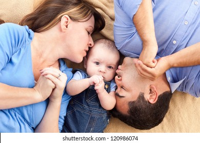 Mixed Race Family With Baby Playing Face Up On The Blanket