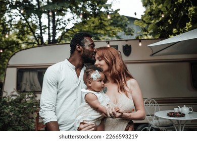 Mixed race family with dark skinned infant daughter spend time together hugs and kisses in camper park. African american man his fair skin wife and little girl enjoying summer vacation in open air - Shutterstock ID 2266593219