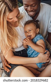 Mixed Race Family Relaxing On Bed Together At Home