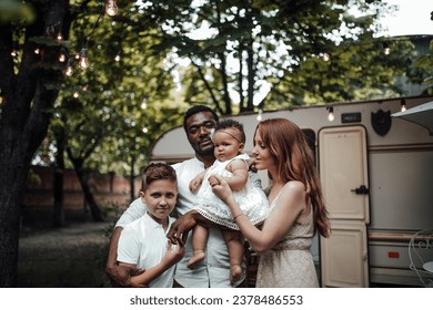 Mixed race family with white son and infant swarthy daughter spend time together in camper park outdoor. African american man with his fair skinned wife and kids enjoying summer vacation in open air - Powered by Shutterstock