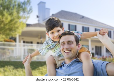 Mixed Race Father and Son Playing Piggyback in Front of Their House.