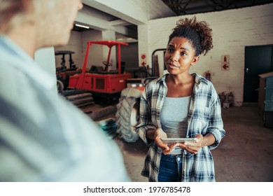 Mixed race female chatting to caucasian male while holding digital tablet - Powered by Shutterstock