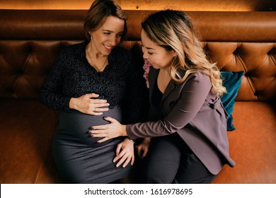 Mixed race female gay couple touching pregnant belly	