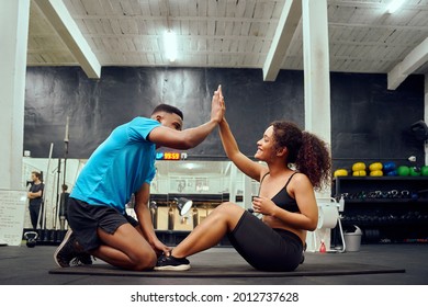 Mixed race friends doing cross fit in the gym. African American male encouraging African American female during sit-ups. High quality photo - Powered by Shutterstock