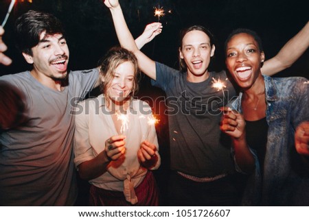 Mixed race friends playing with sparklers celebration and festive party concept