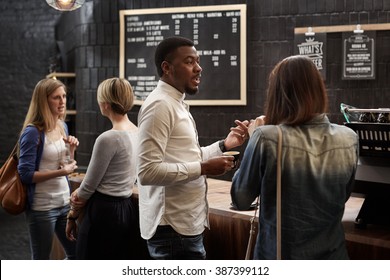 Mixed Race Friends Talking At The Counter Of Coffee Shop