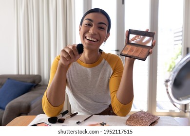 Mixed race gender fluid man making vlog holding foundation powder makeup and brush, smiling. staying at home in isolation during quarantine lockdown. - Powered by Shutterstock