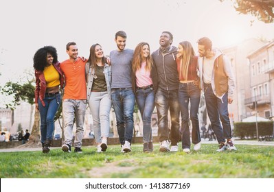 Mixed Race Group Of Friends Having Fun Walking Outdoors Hand On Shoulders. Young People Community Walking Together. Integration And Diversity Concept.