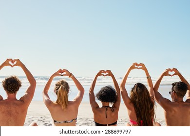 Mixed Race Group Of Friends Making Heart Shapes With Hands Raised Up To The Sky Show A Love Of Summer And Sunshine Shot From The Back