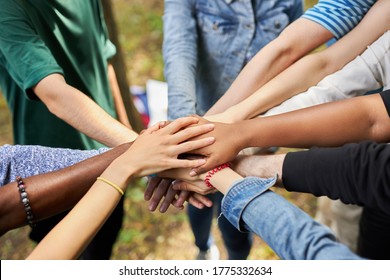 mixed race international group of young people gathered outdoors, they holds hands together. friendship concept. make love, not war