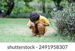 Mixed race little boy exploring the nature with magnifying glass outdoors, children playing in the park with magnifying glass. Curious kid exploring nature by magnifier