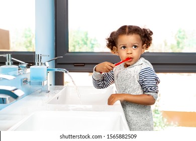 Mixed Race Little Cute Girl Brushing Teeth Standing At Bathroom Looking Aside Pensive