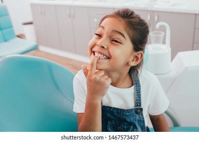 Mixed race little patient showing her perfect toothy smile while sitting dentists chair - Shutterstock ID 1467573437