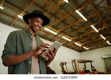 Mixed Race Male Farmer Typing On Digital Tablet Standing In Farm Dairy 