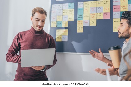 Mixed Race Man Talking With Scrum Master Using Laptop