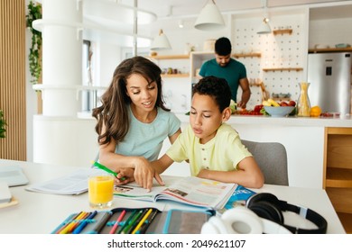 Mixed Race Mother Is Helping Her Son To Finish His Homework. Son Is Listening To His Mother And Writing Down The Answers.