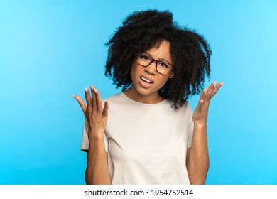 Mixed race shocked female portrait with frowning open mouth, angry surprised face expression on blue background. Young black girl confused with bad news. Casual afro lady with curly hair upset amazed