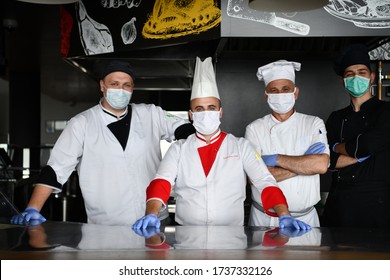 Mixed Race Team Portrait Of Group Chefs Standing Together In The Kitchen At Restaurant Wearing Protective Medical Mask And Gloves In Coronavirus New Normal Concept