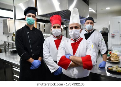 Mixed Race Team Portrait Of Group Chefs Standing Together In The Kitchen At Restaurant Wearing Protective Medical Mask And Gloves In Coronavirus New Normal Concept