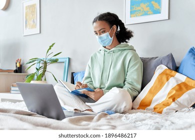 Mixed Race Teenage Girl Wearing Face Mask Remote Studying Online At Home. African Teen Distance Learning Watching Webinar, Virtual School Class With Teacher Using Laptop Studying During Coronavirus.