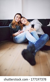 Mixed Race Teenage Guy Holding Remote Control Relaxing With His Beautiful Girlfriend At Home. Loving Young Couple Sitting Together On Floor Watching TV.