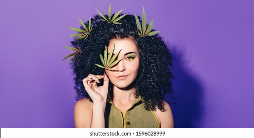 Mixed race woman with Afro-curls holding hemp Leaf. The concept of legalization of marijuana and Cannabis