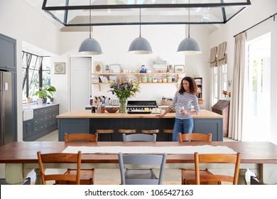 Mixed Race Woman Leaning On Kitchen Island In Open Plan Home