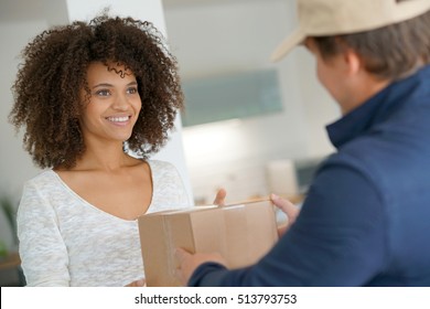 Mixed Race Woman Receiving Package From Delivery Man