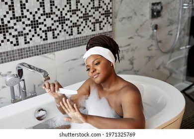 Mixed Race Woman Sitting On Bathtub Taking Care Of Nails, Doing Manicure With Nailfile