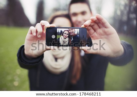 Mixed race young boy and girl making a funny face while taking a self portrait with mobile phone. Cute young couple photographing themselves with smartphone.