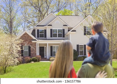 Mixed Race Young Family Looking At Beautiful New Home.