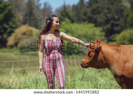 Mixed race young woman feeds cows on a farm